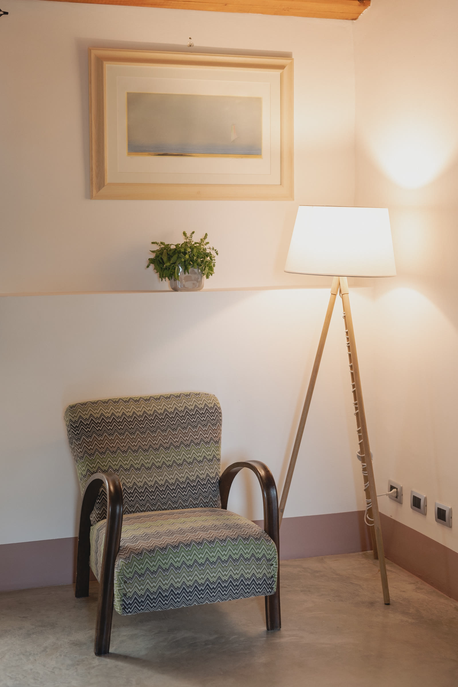 Una poltrona sotto un quadro e una lampada