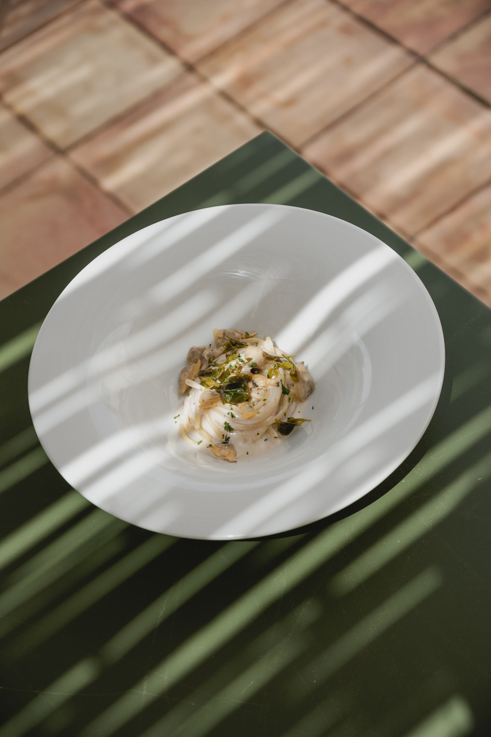 Un piatto bianco con un antipasto, in una luce a strisce sul tavolo